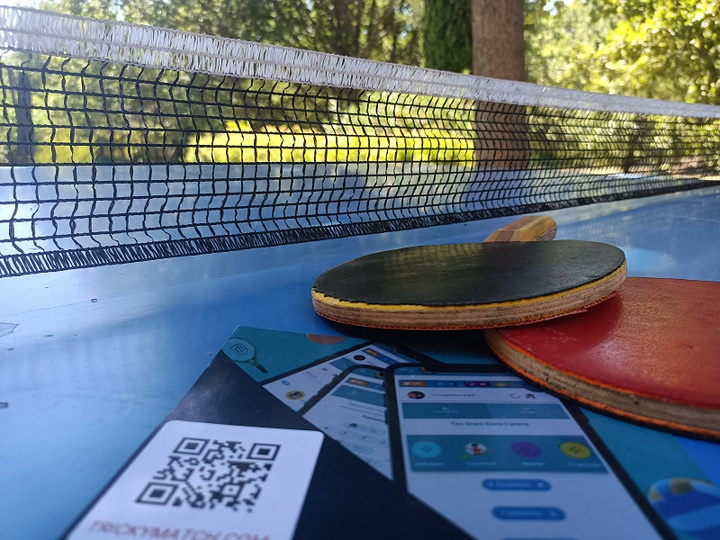 table de ping pong avec raquettes et filet, et flyers d'invitation à l'Arena TrickyMatch. 